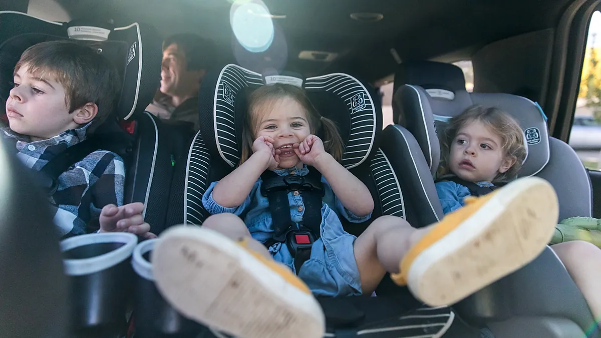 Drei Kinder in Kindersitzen auf der Rückbank eines USA-Mietwagens – Kindersitze verringern die Innenraumflexibilität und den Zugang zur dritten Reihe