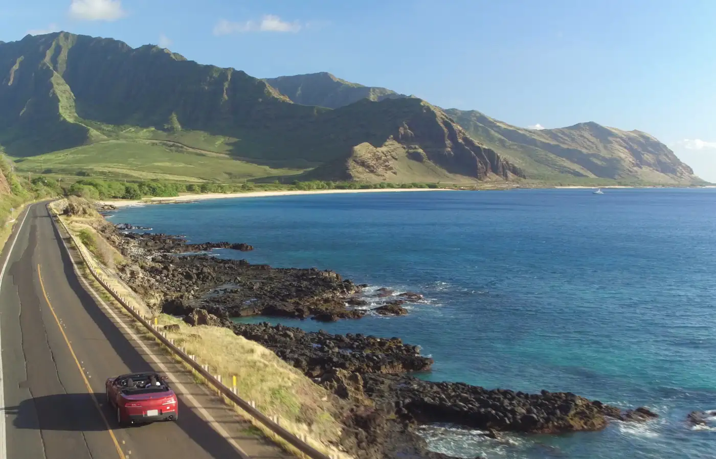 Rotes Cabrio als Mietwagen an einer Küstenstraße auf Hawaii als Sinnbild für die begrenzte Inselflotte gefragter Jeeps, Cabrios und Minivans