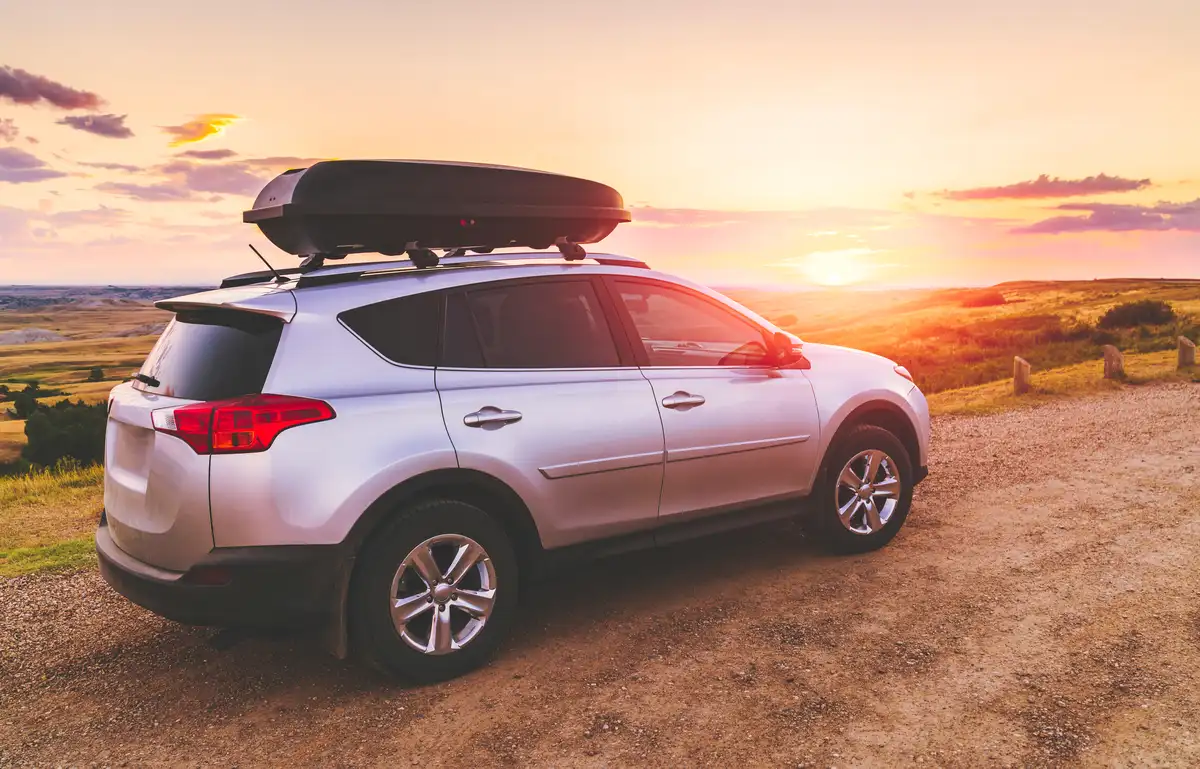 SUV-Mietwagen mit montierter Dachbox bei Sonnenuntergang – eine spontane Dachlösung ist beim Mietwagen kein verlässlicher Plan B