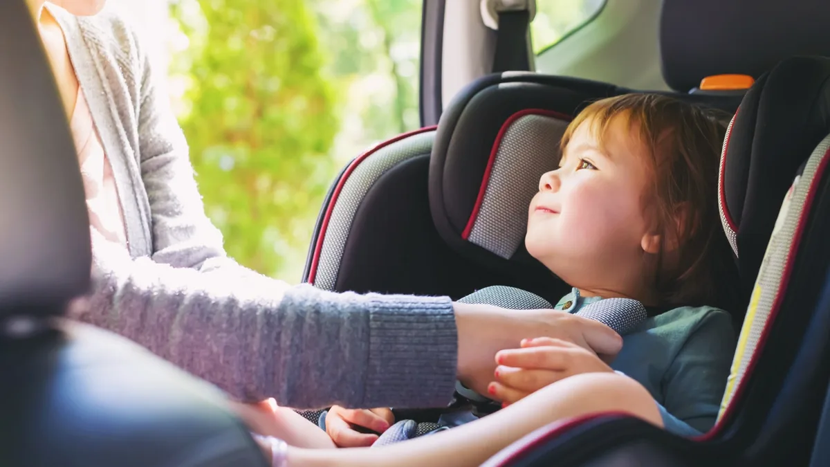 Kind wird in einem Kindersitz im Auto angeschnallt